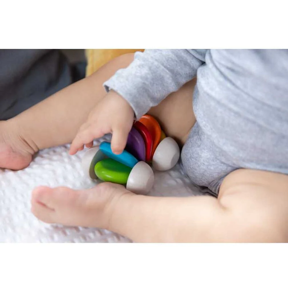 baby with rainbow baby car from plan toys