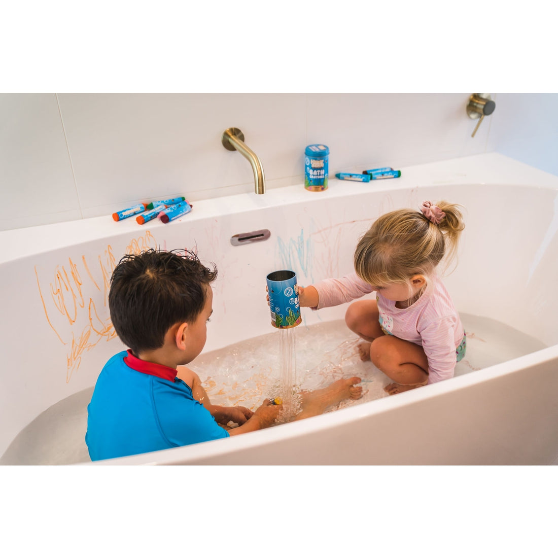 Two children playing in a bath with Bath Crayons