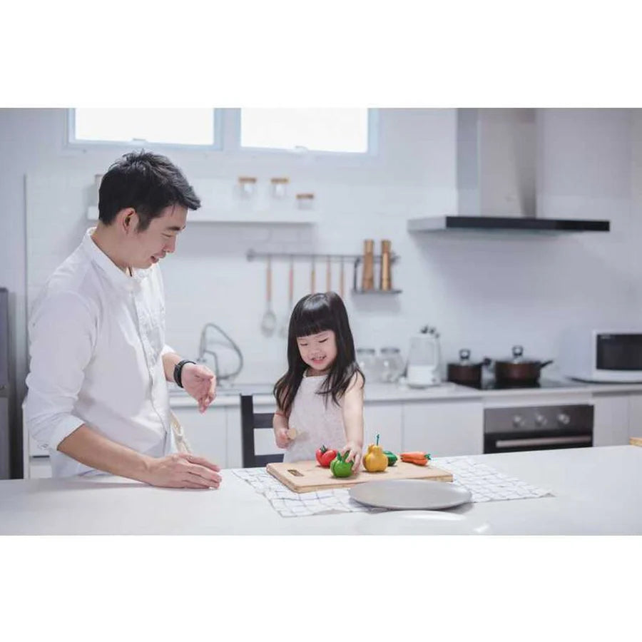 child and their parent playing with wonky fruits and vegetables on a kitchen table