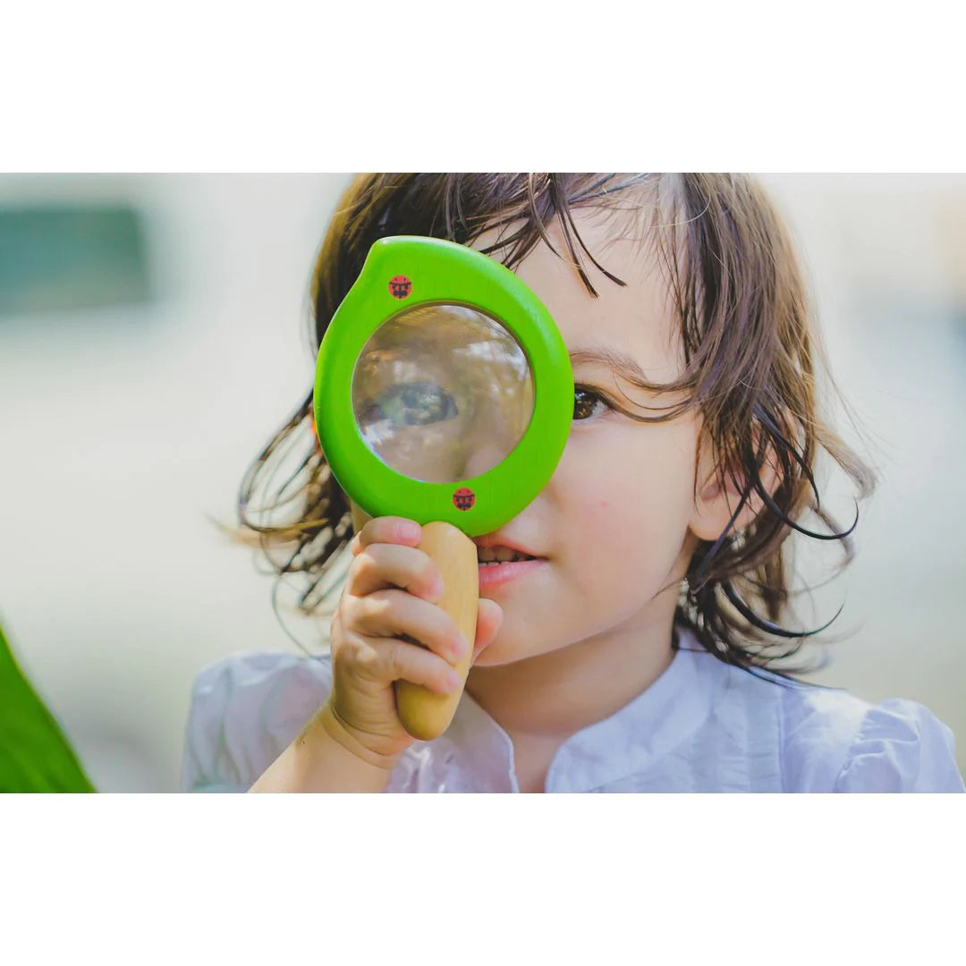 child looking through a leaf magnifier