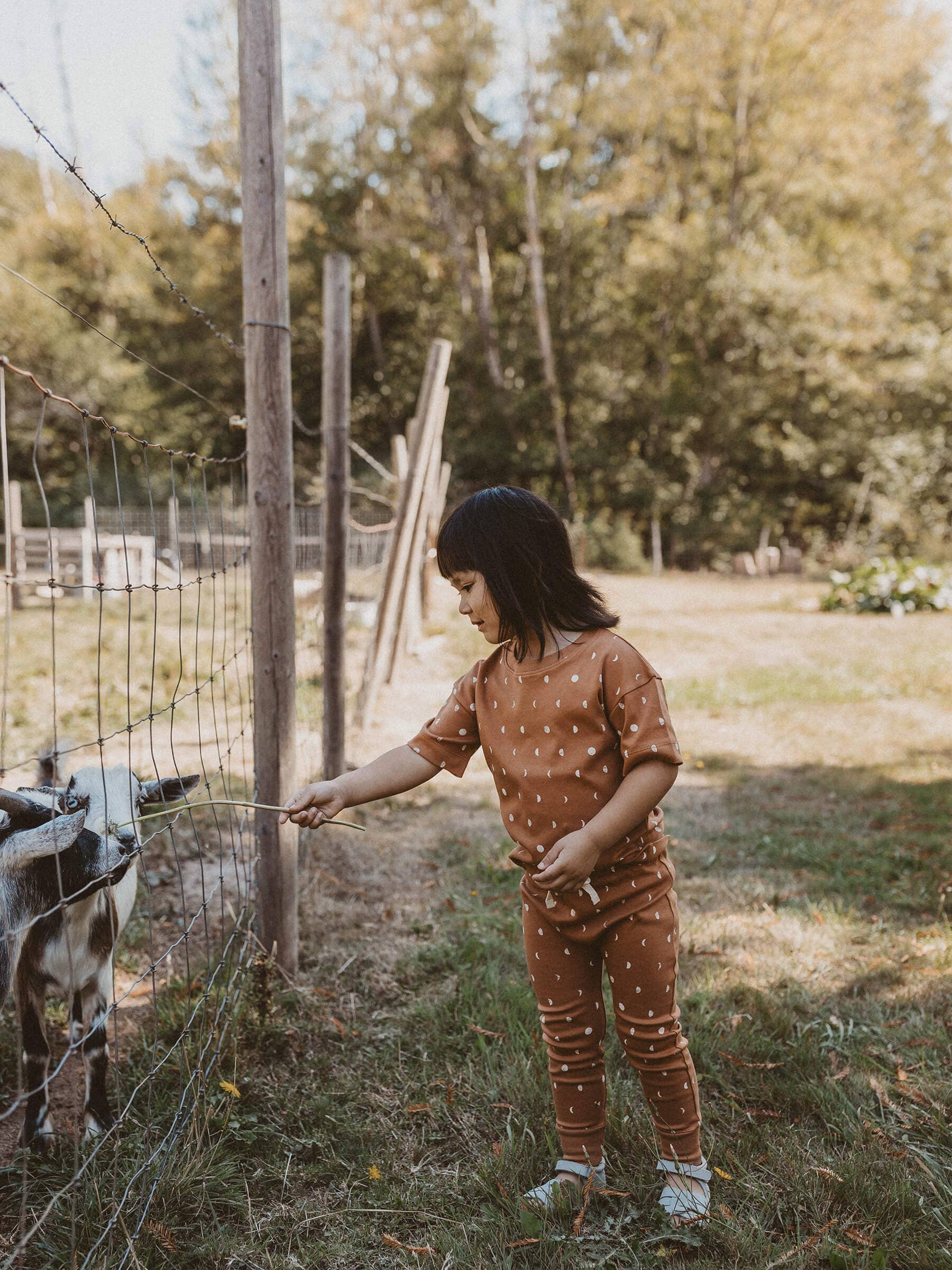 child standing outside wearing terracotta moon organic short sleeve tee and drawstring pants