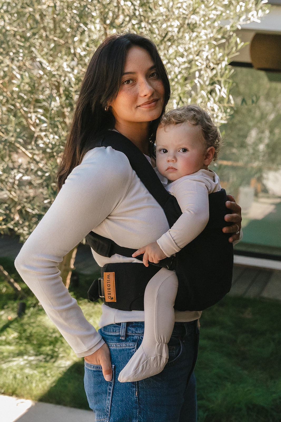 Woman holding a baby in a carrier outdoors
