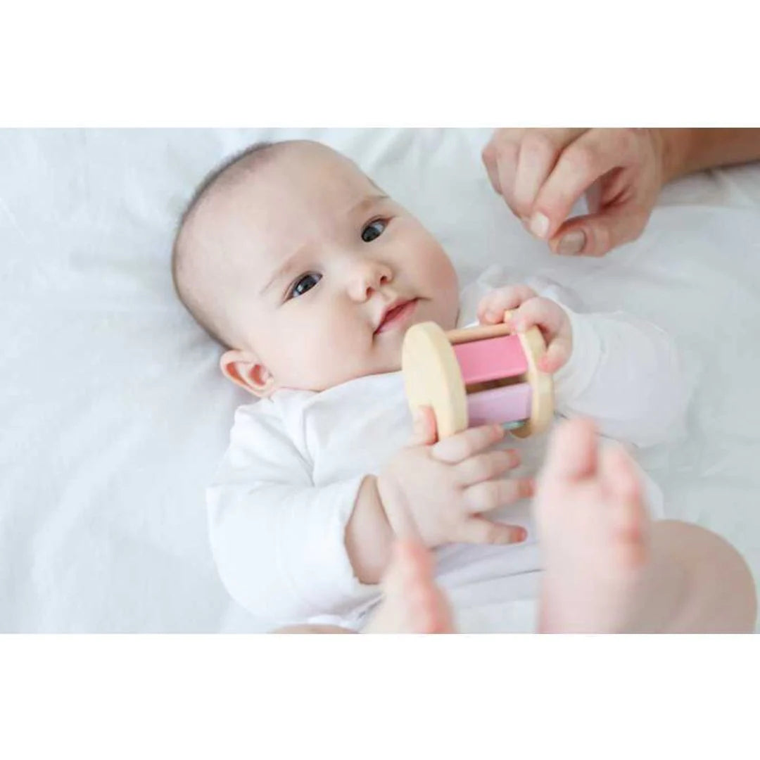 Baby laying on a bed holding pastel roller with sound