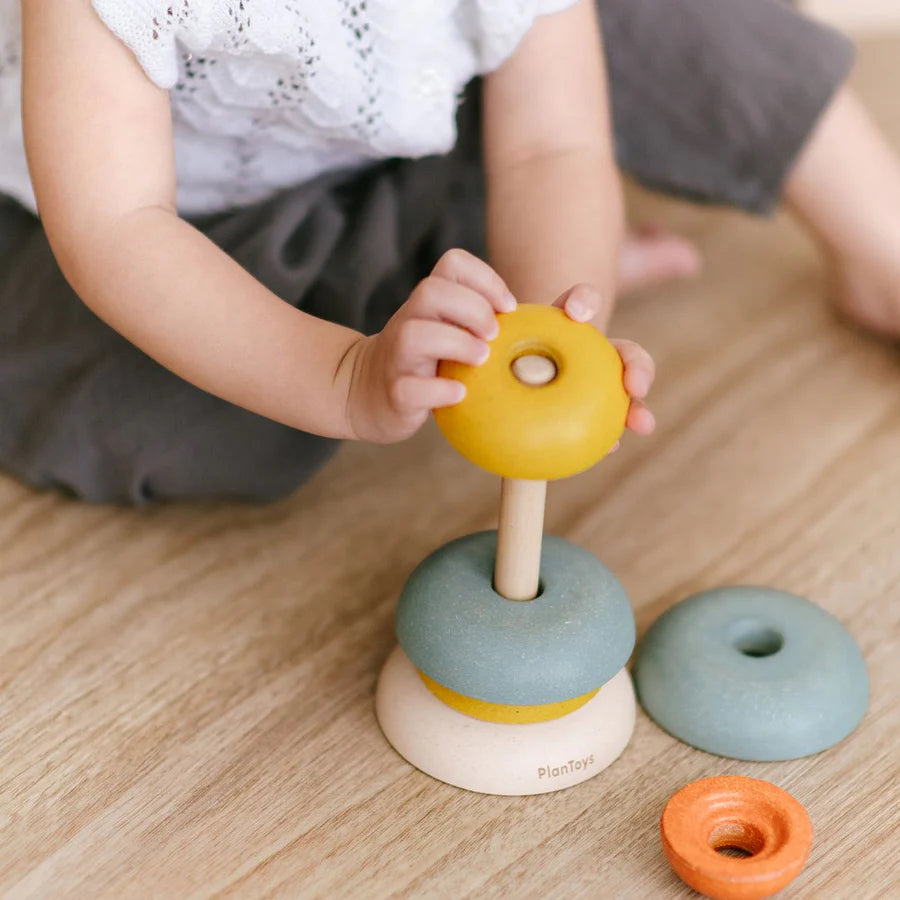 Close-up of child sitting on the floor and playing with stacking ring cups