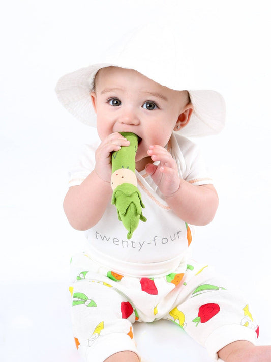 baby wearing a sun hat teething on an organic plush asparagus