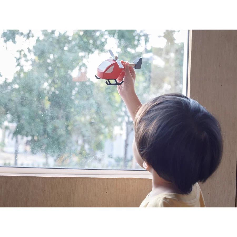 Child playing with helicopter by PlanToys in front of a window