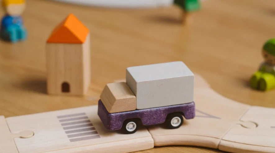 purple delivery truck on a wooden road