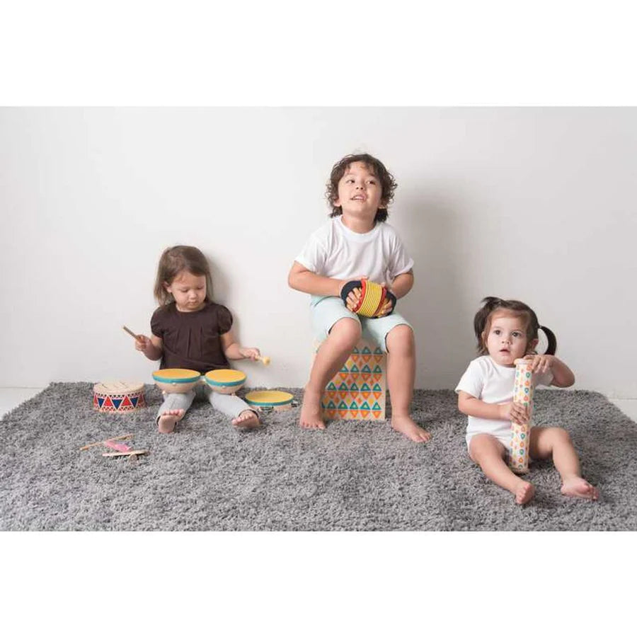 Children sitting on a grey rug playing with musical instruments by PlanToys