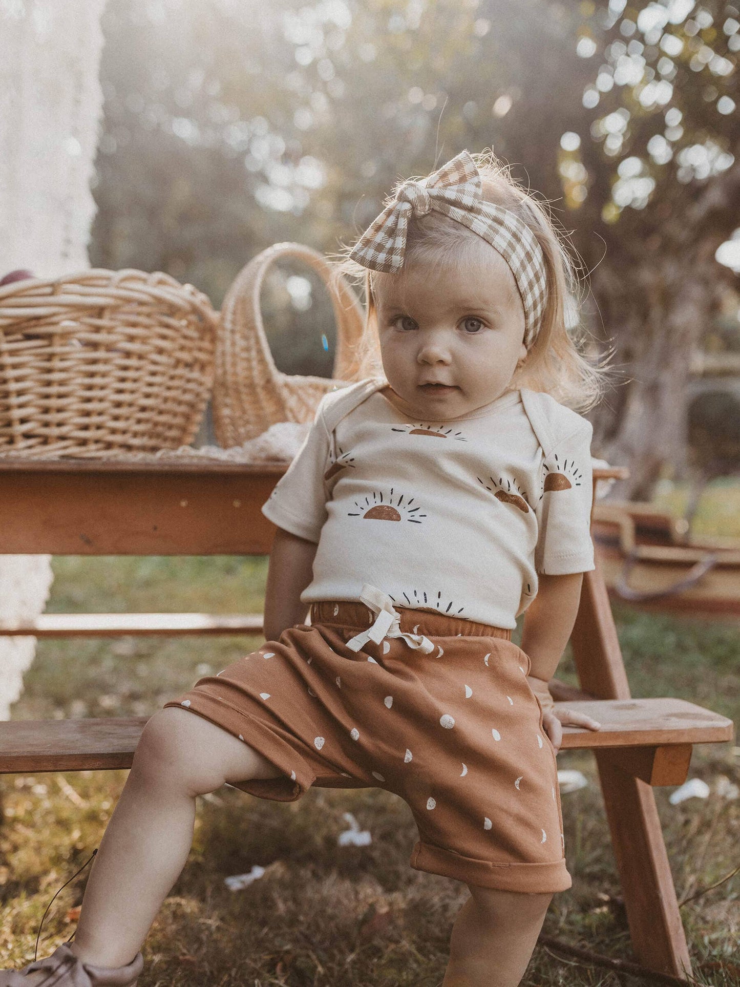 baby sitting at a picnic table wearing sun organic short sleeve onesie
