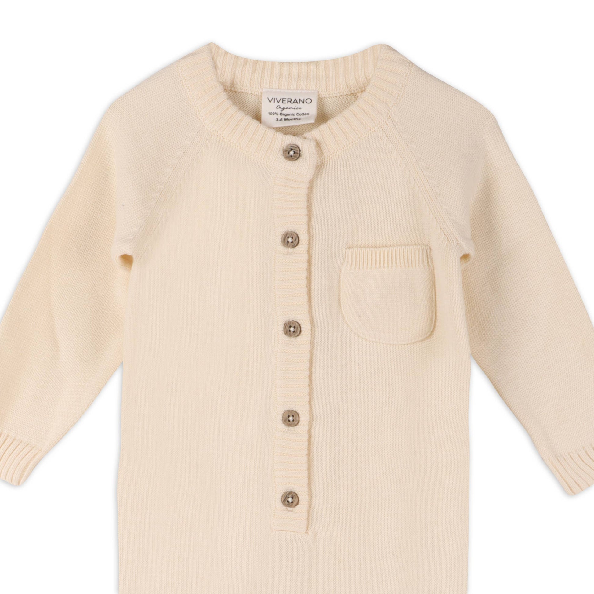 Cream knit romper with button details on a white background