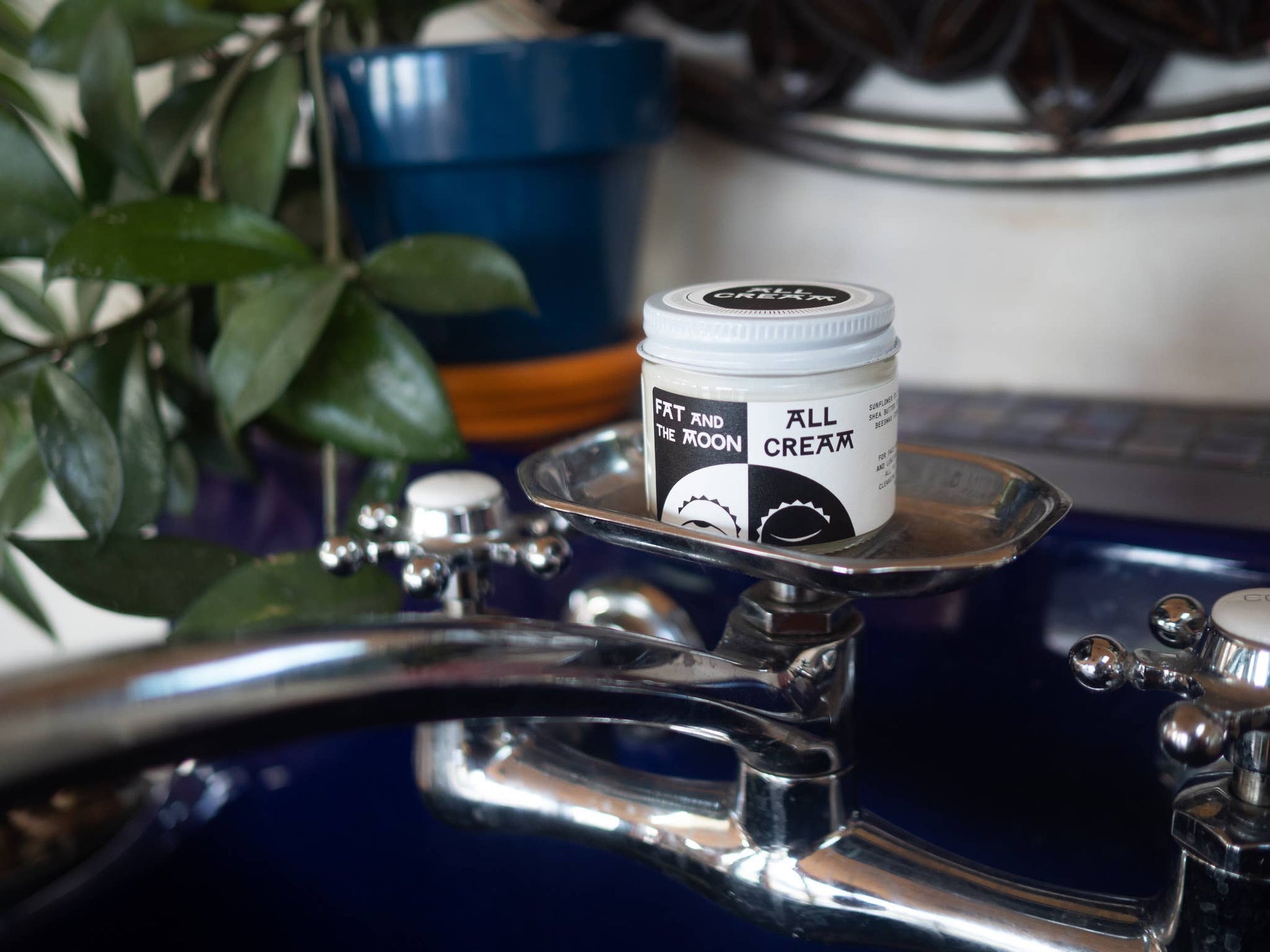 Jar of 'All Cream' on a metallic surface with a blurred background