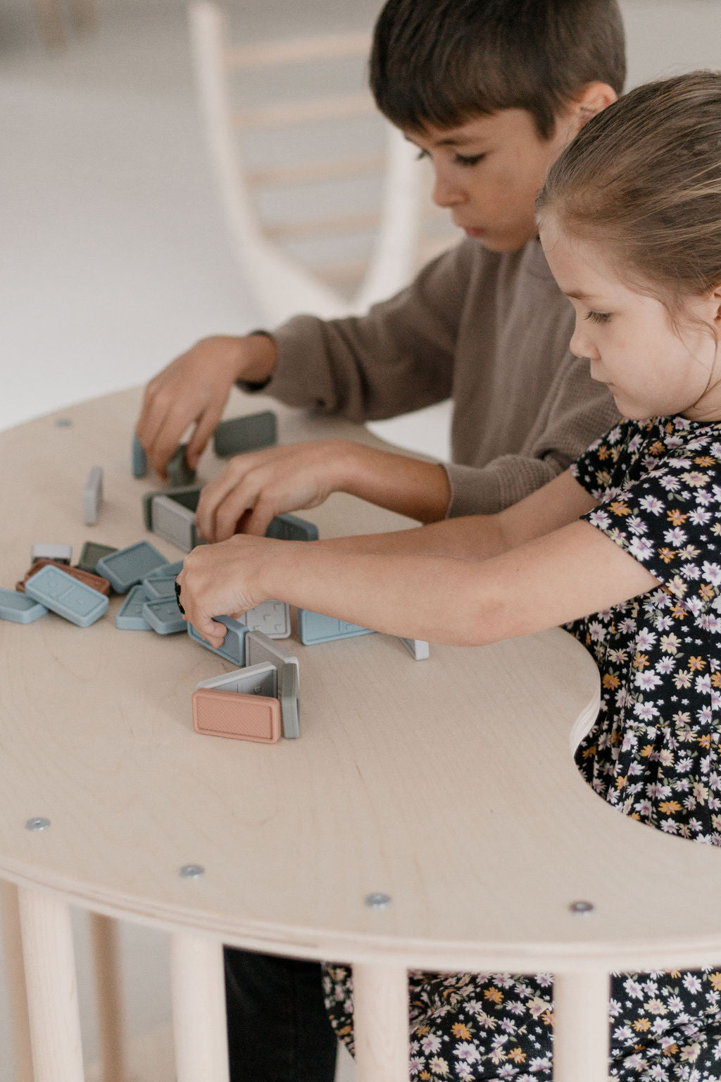 Two children playing with building blocks at a round table.