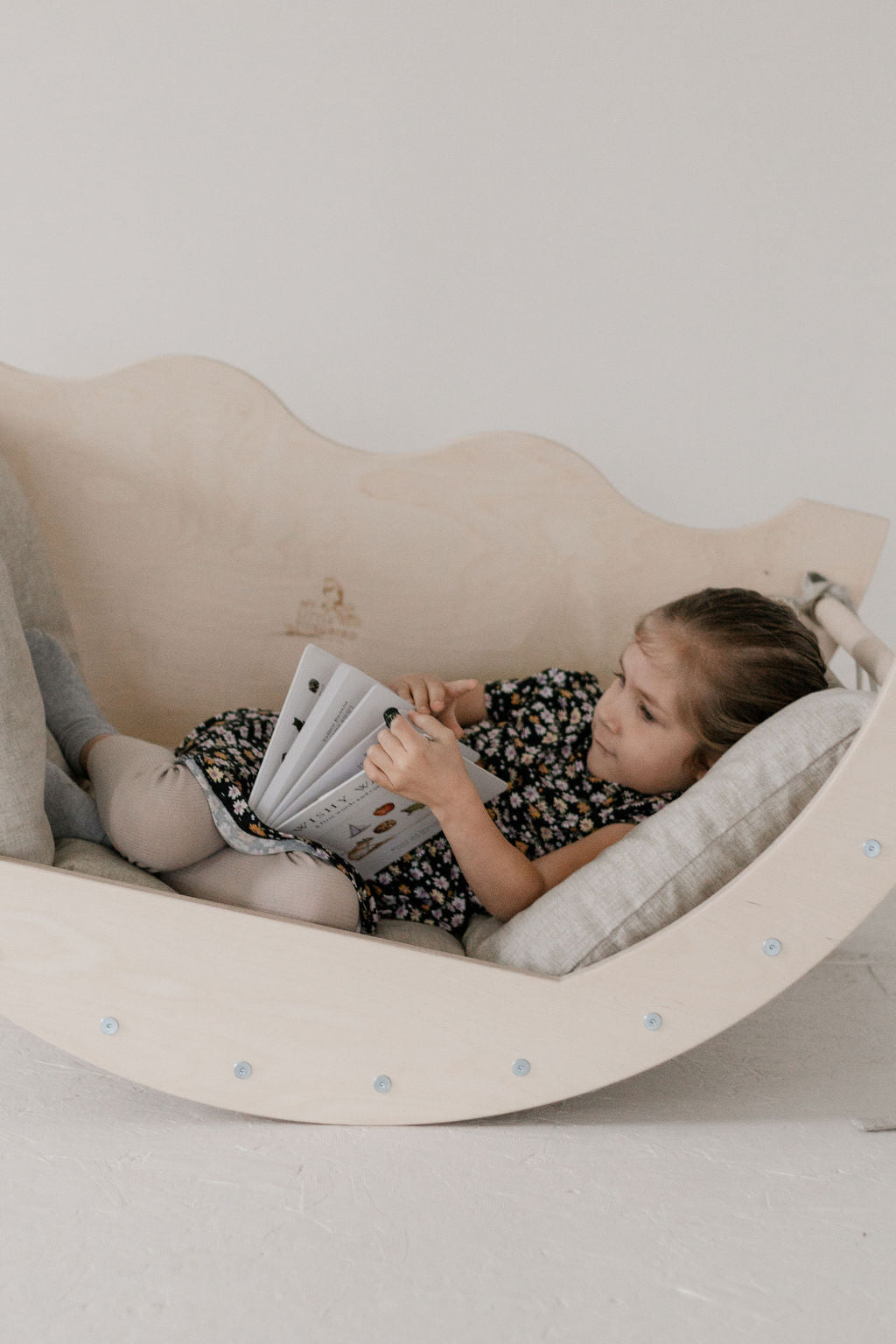 Child reading a book in a wavy chair with a plain background