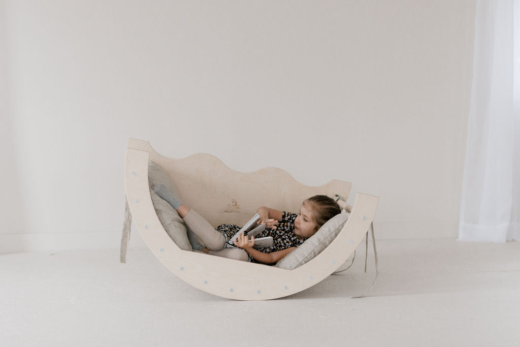 Child lying on a modern, curved chair against a plain background