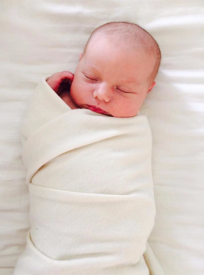 Newborn baby wrapped in a white blanket on a white background