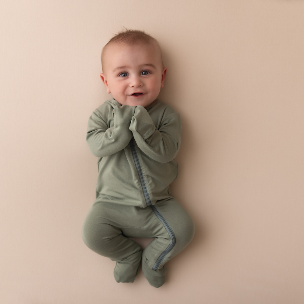 Baby wearing a green onesie on a beige background