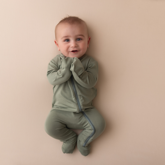 Baby wearing a green onesie on a beige background