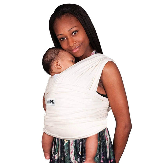 Woman holding a baby in a white baby carrier against a white background