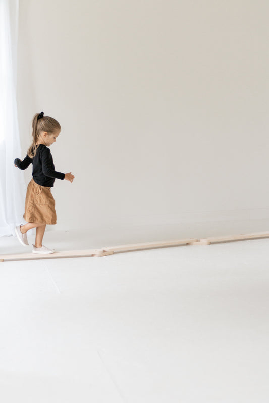 Child standing on a balance beam in a minimalistic setting