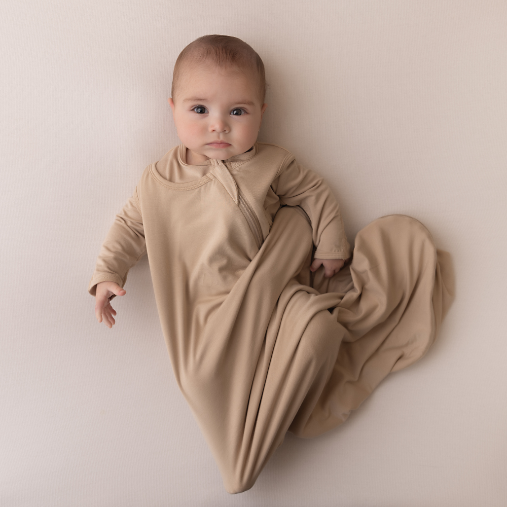Baby in a beige swaddle on a plain background