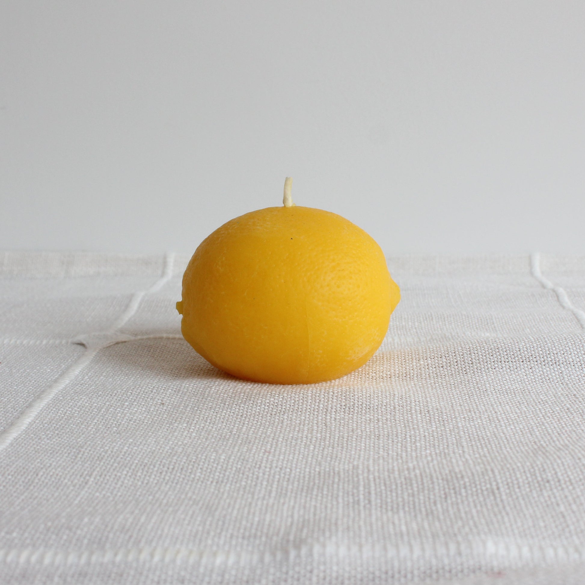 Yellow candle on a textured white surface
