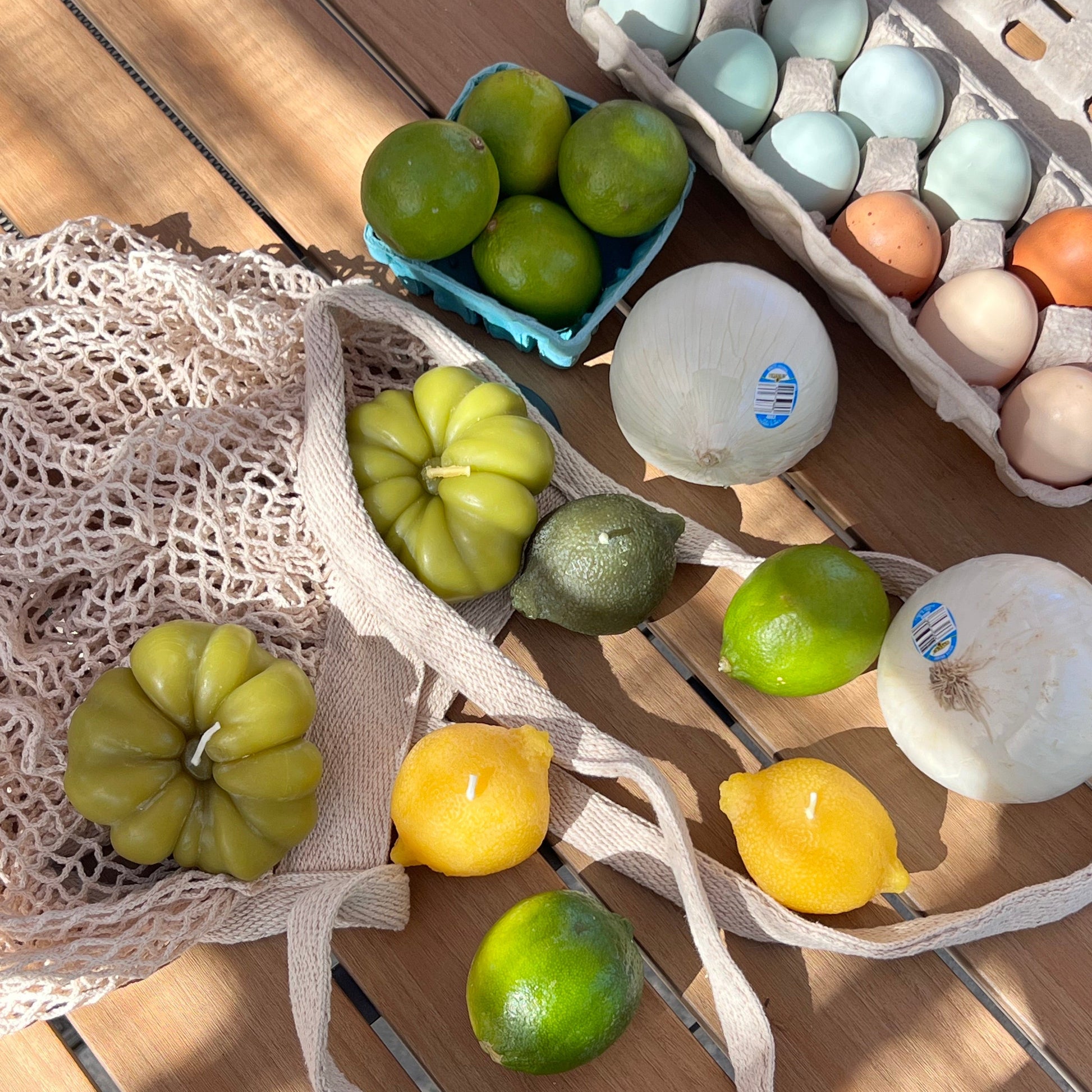 Fruits and vegetables on a wooden surface with a net bag and carton of eggs.