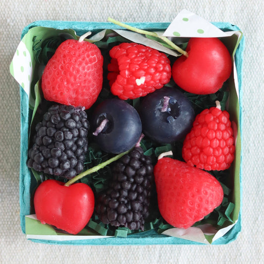Box of assorted berry-shaped candles on a textured surface