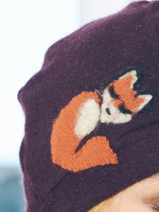 Purple beanie with a fox embroidered on it against a blurred background