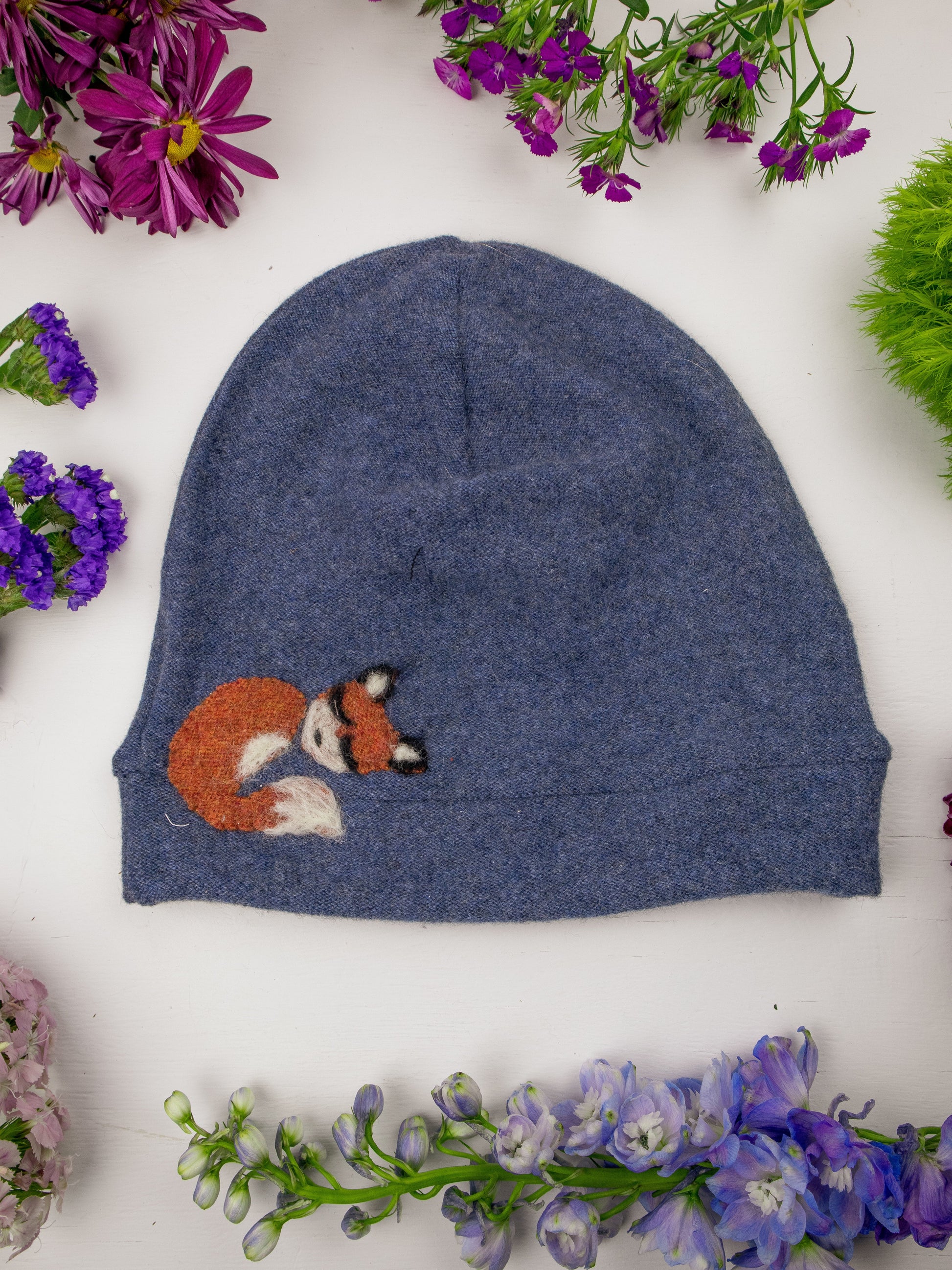 Blue beanie with fox design on a white background with flowers