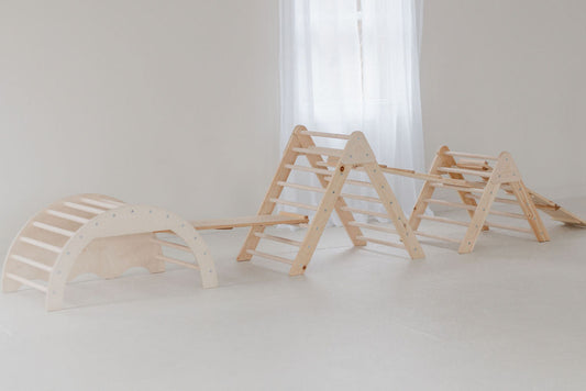 Set of wooden children's play structures on a white floor with a light curtain in the background.