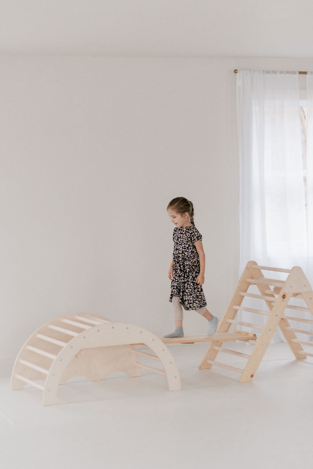 Child playing with wooden climbing toys in a minimalistic room
