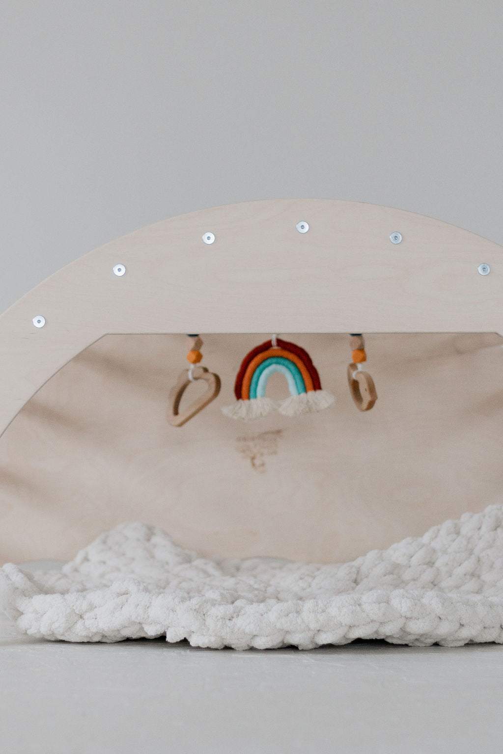Wooden shelf with decorative items including a rainbow and cloud on a light gray background