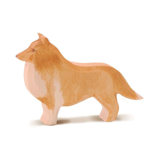 handcarved wooden blonde collie dog standing by ostheimer on a white back ground