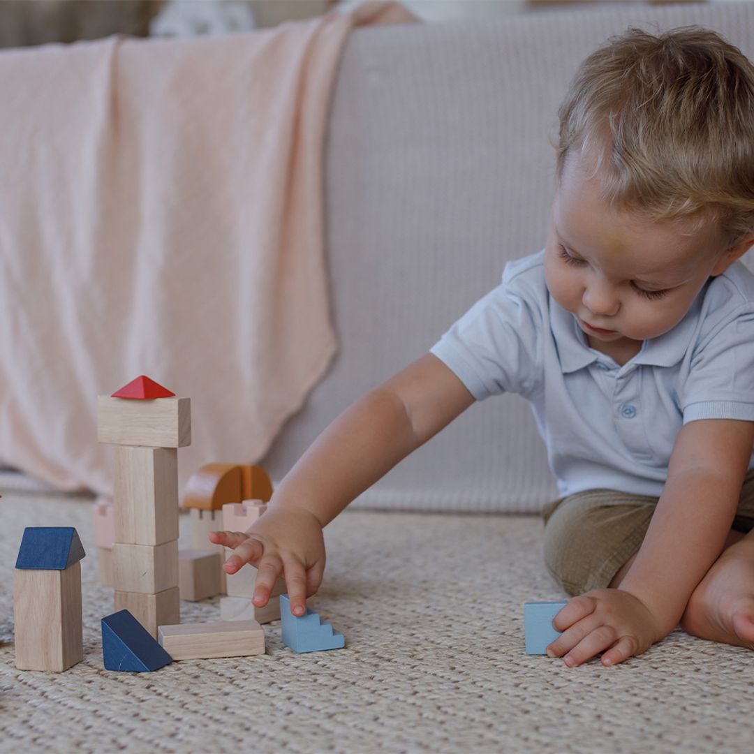 Child playing with wooden blocks on a carpeted floor