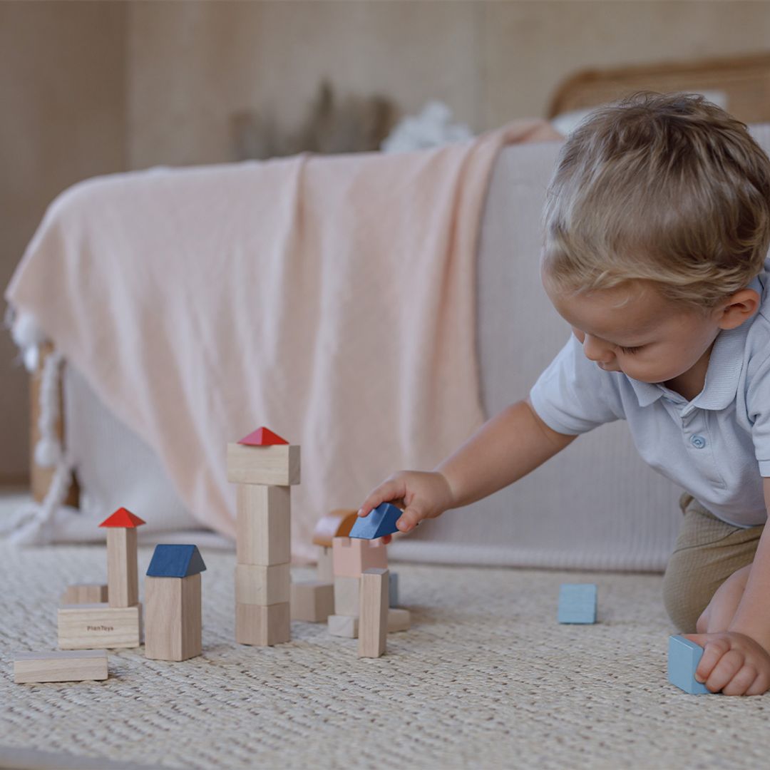 Child playing with wooden blocks on a carpeted floor