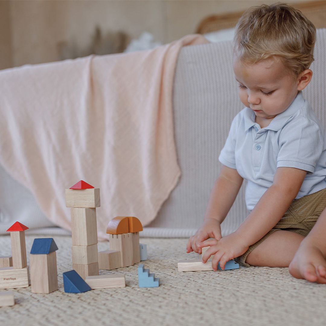 Child playing with wooden blocks on a bed