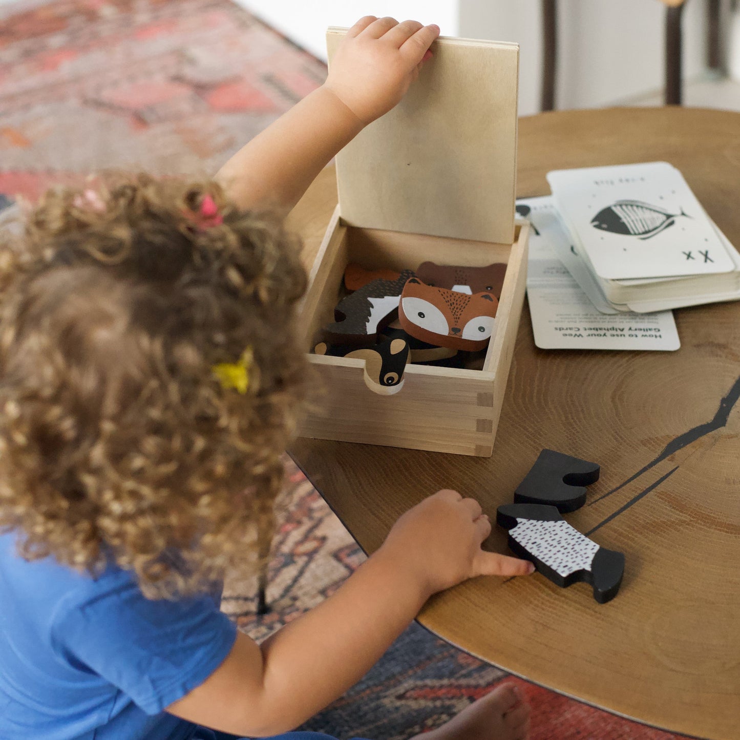 Child playing with wooden animal toys on a table