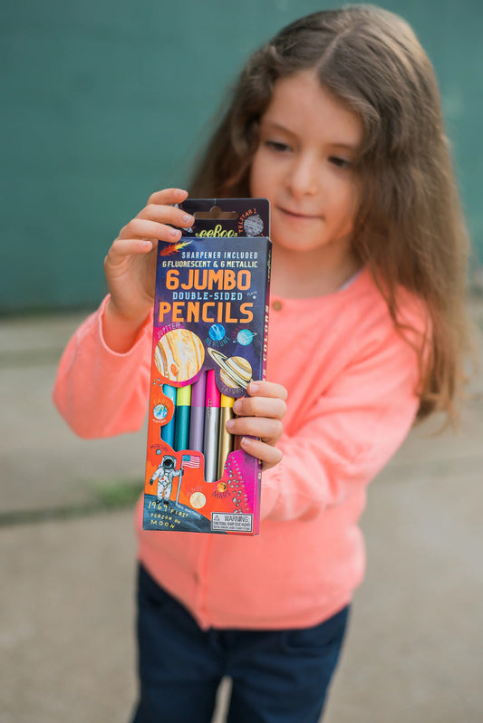 child wearing a pink sweater holding a box of solar system double sided jumbo pencils by eeBoo