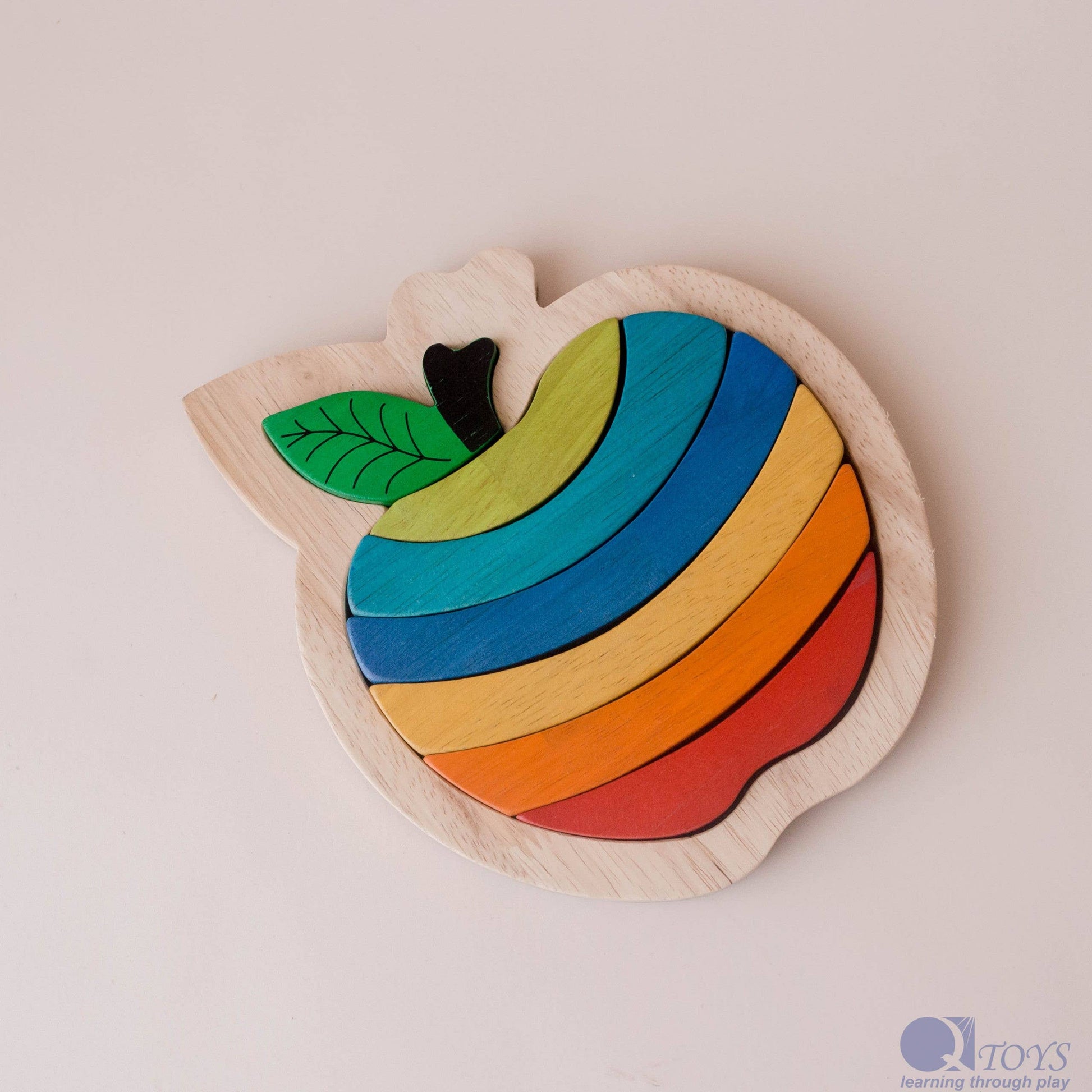 Colorful wooden apple-shaped puzzle toy on a light background