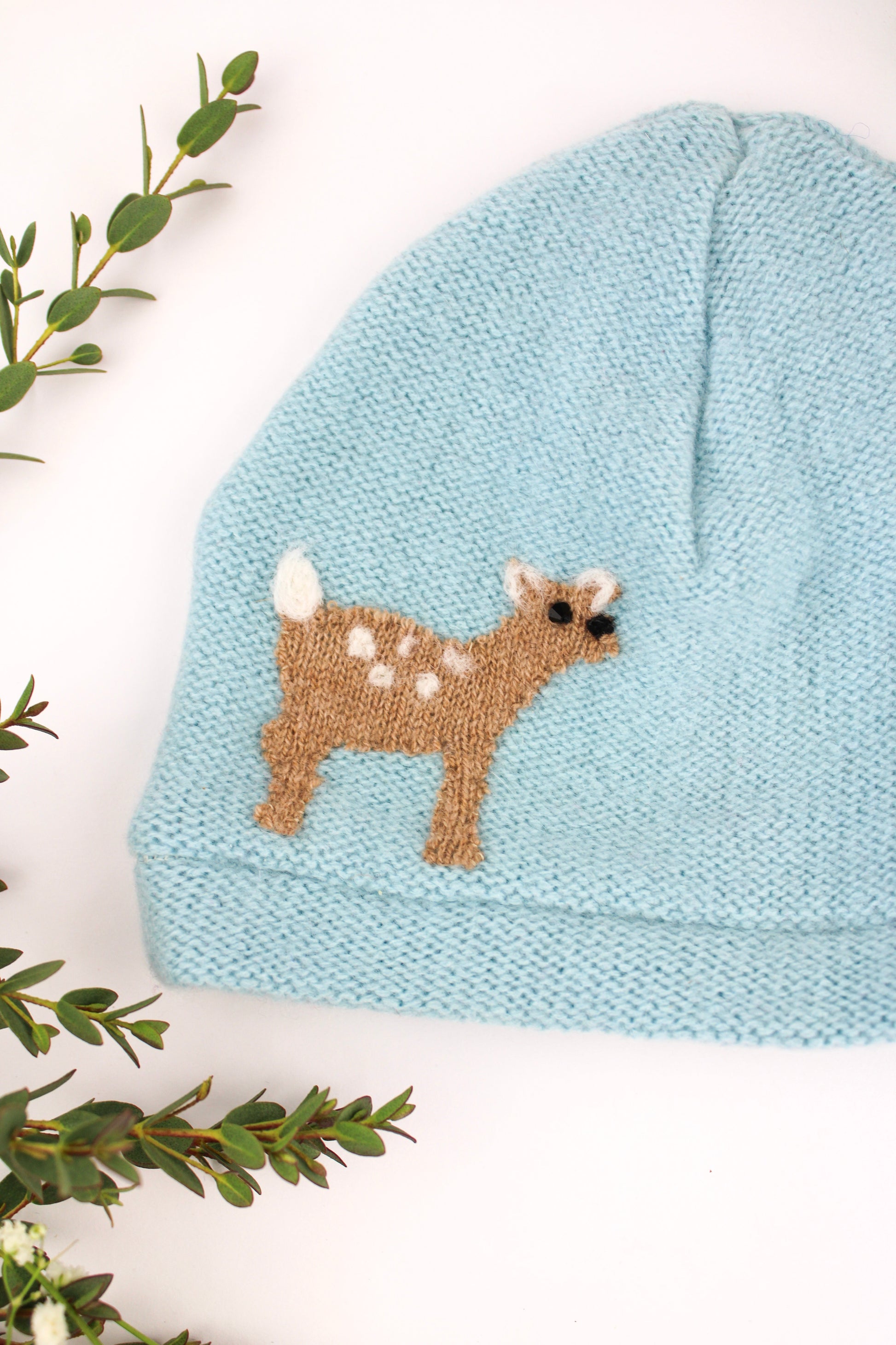 Knitted baby hat with a deer design on a white background