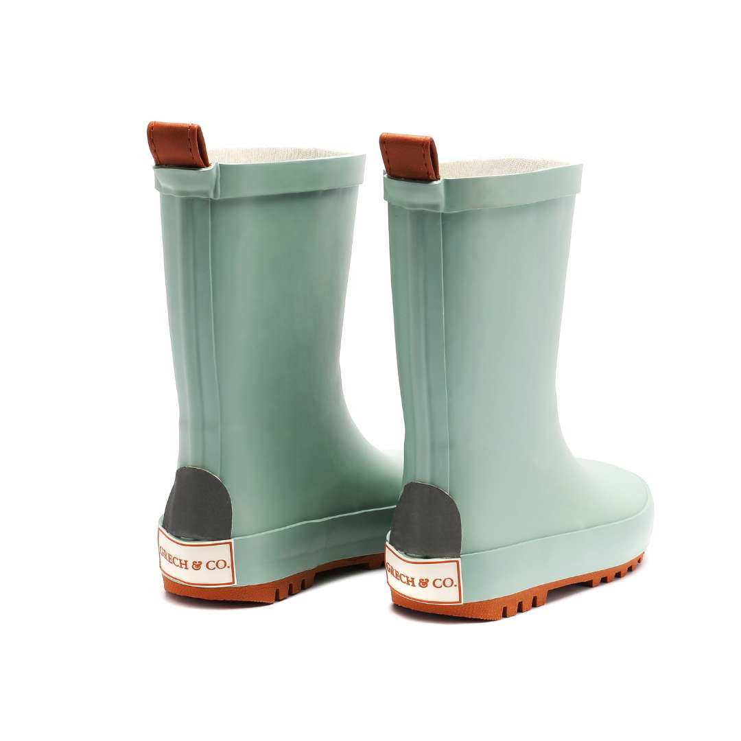 Pair of light green rain boots with brown accents on a white background