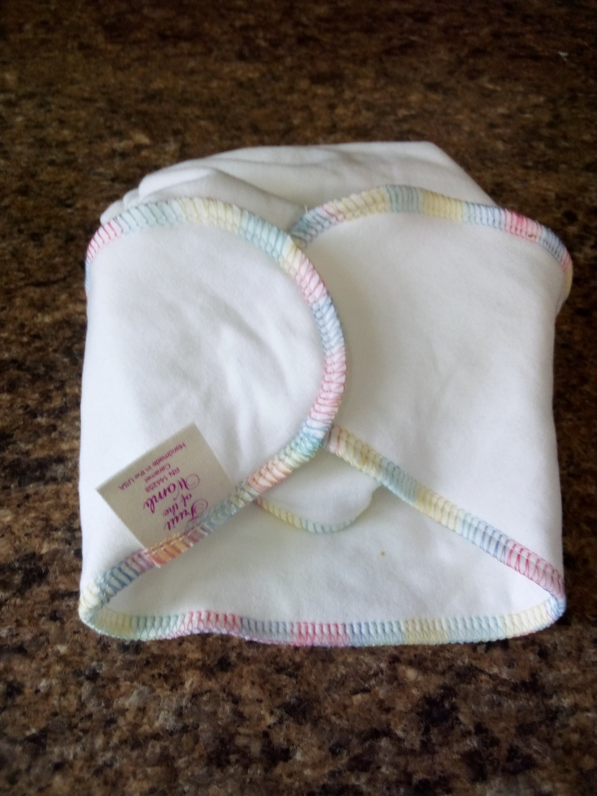 Folded white cloth with colorful trim on a brown surface