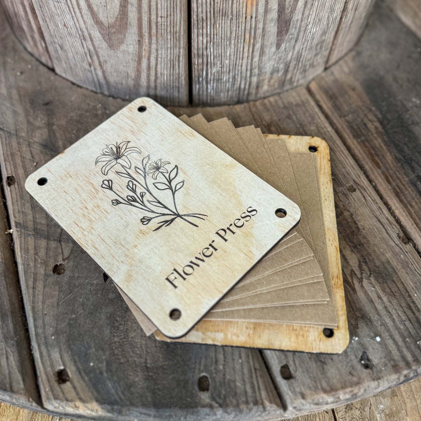 Wooden 'Flower Press' card with floral design on a wooden surface