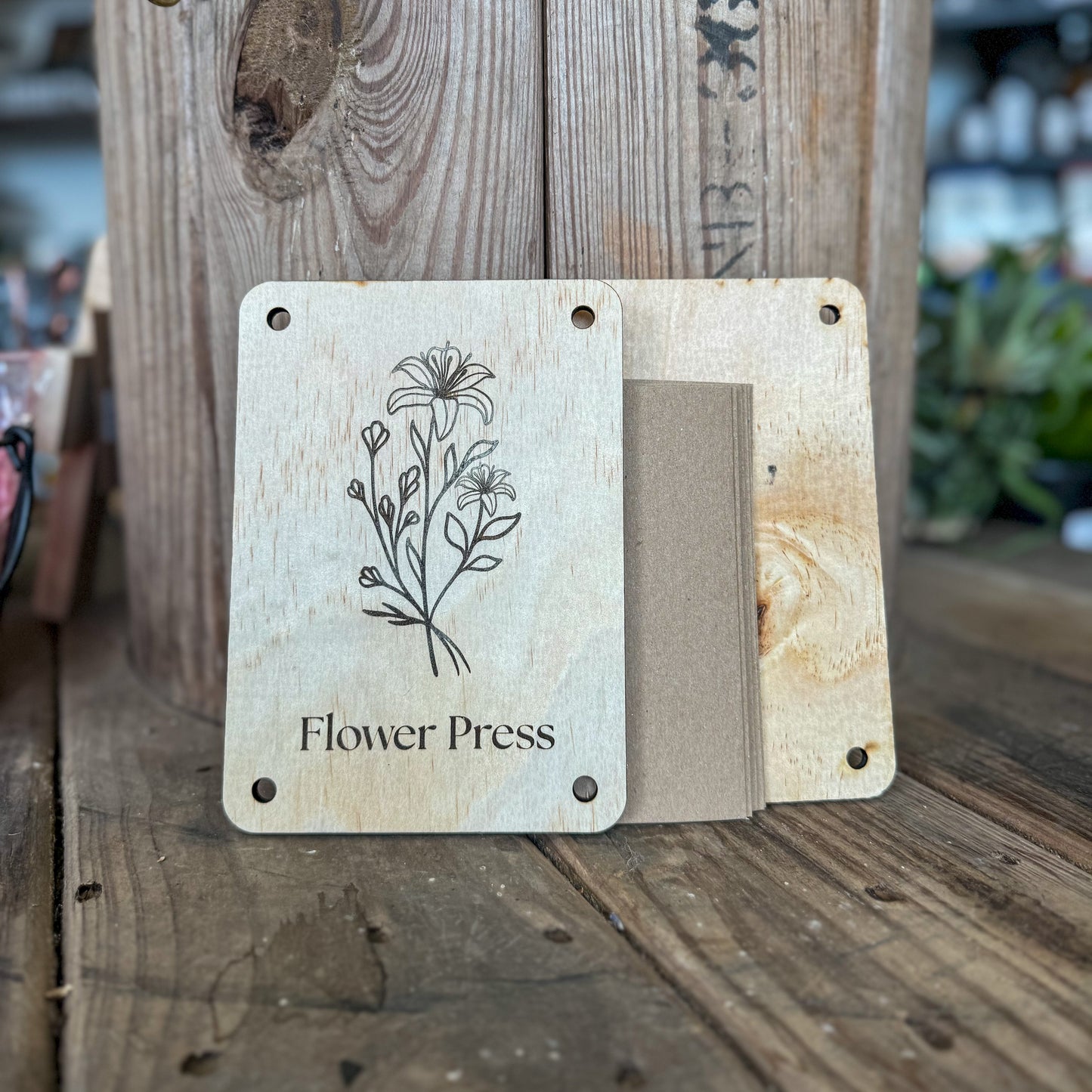 Wooden flower press with floral design and 'Flower Press' text on a wooden surface.