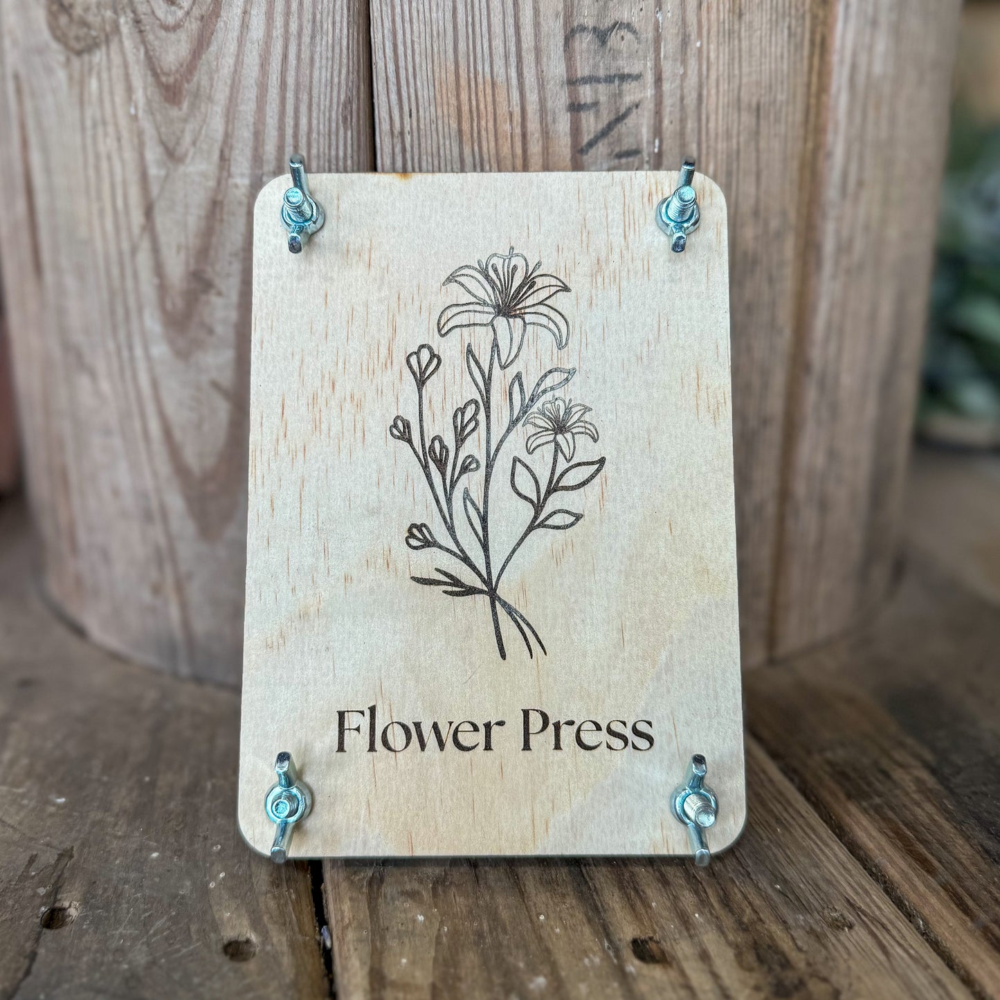 Wooden flower press with floral design and 'Flower Press' text on a wooden background