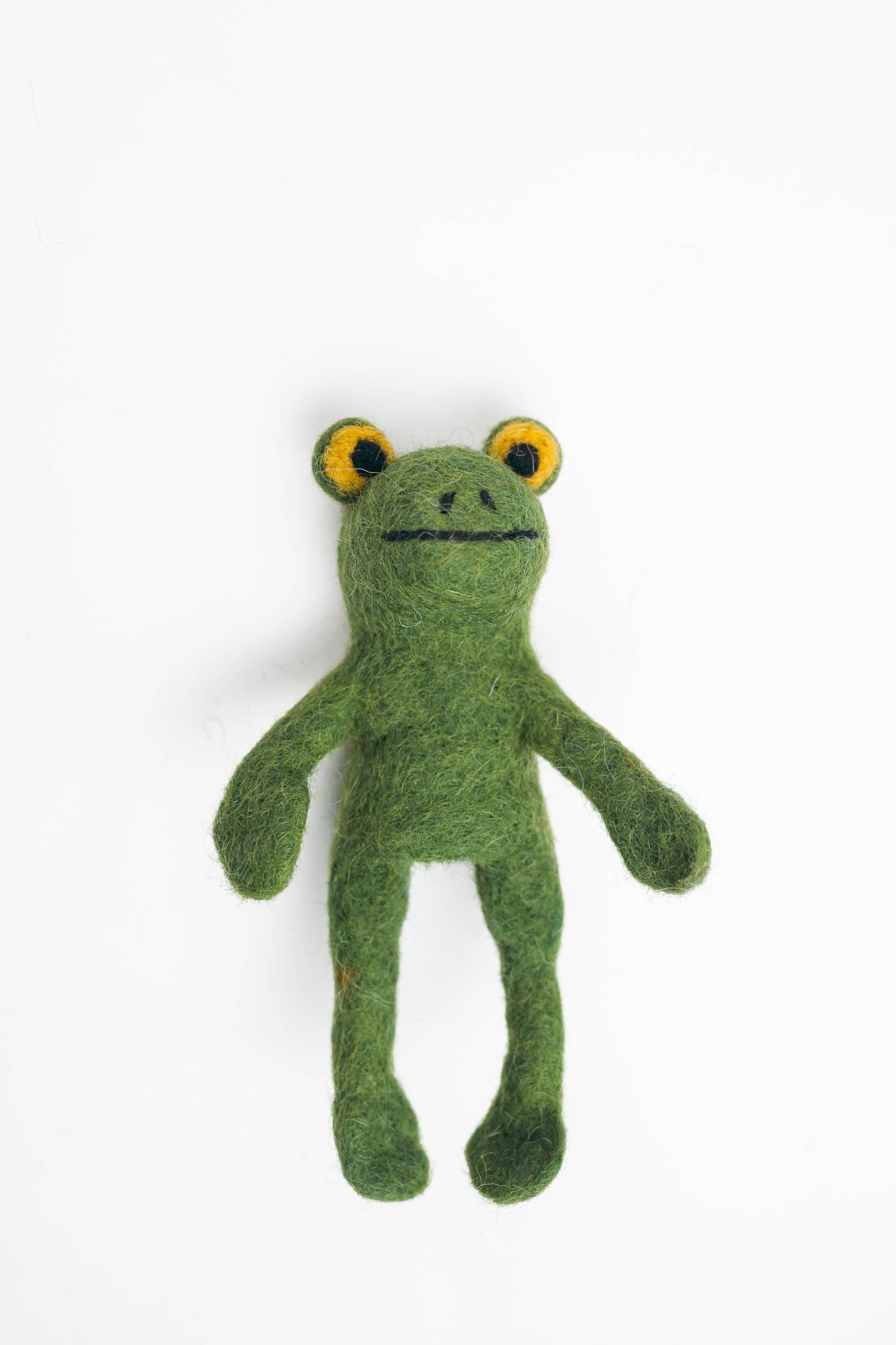 Green felted frog toy on a white background