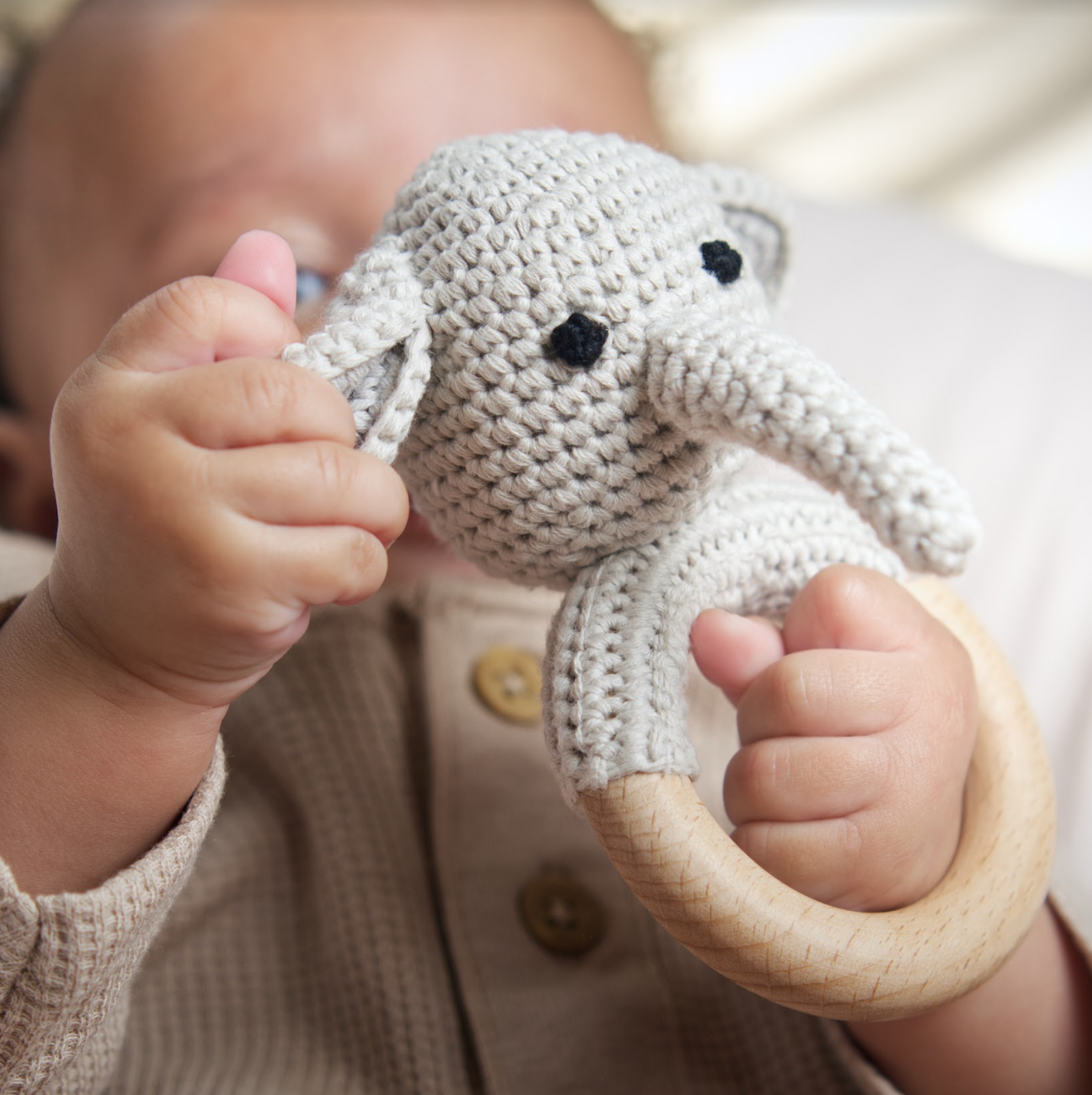 Baby holding a crocheted elephant rattle toy