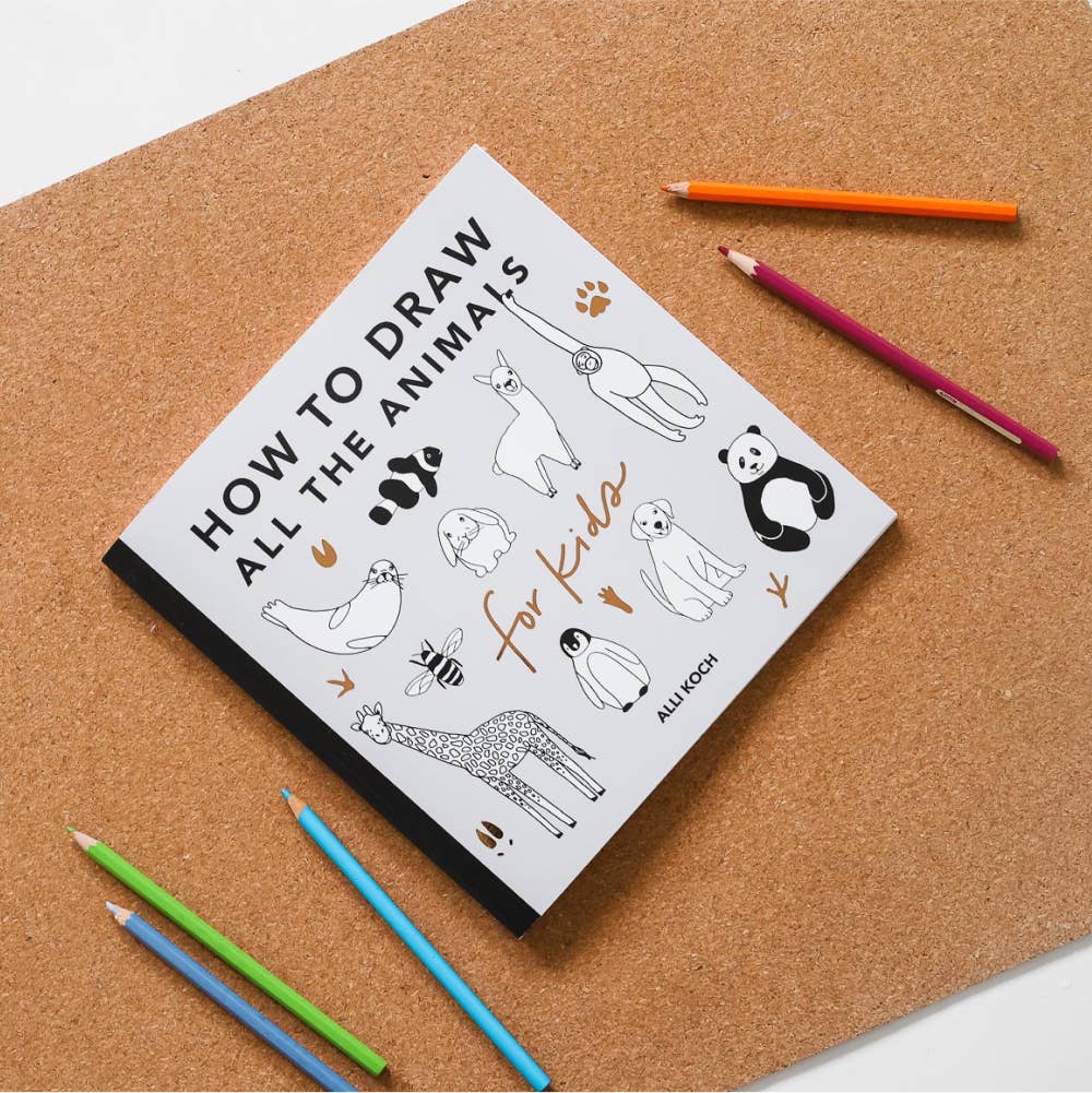 Notebook titled 'How to Draw All the Animals for Kids' on a cork board with colored pencils.