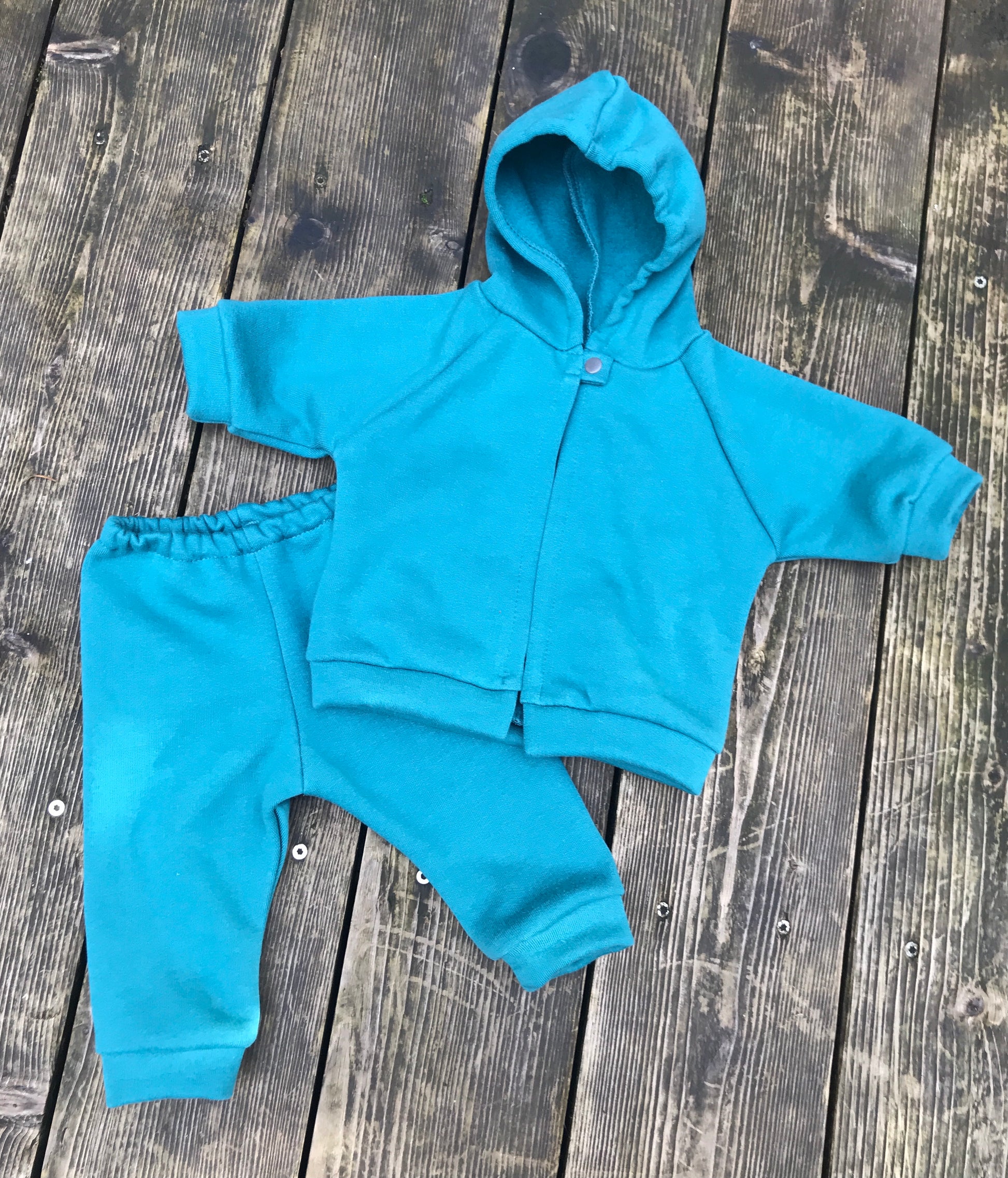 teal baby hoodie and pants set on a wooden surface