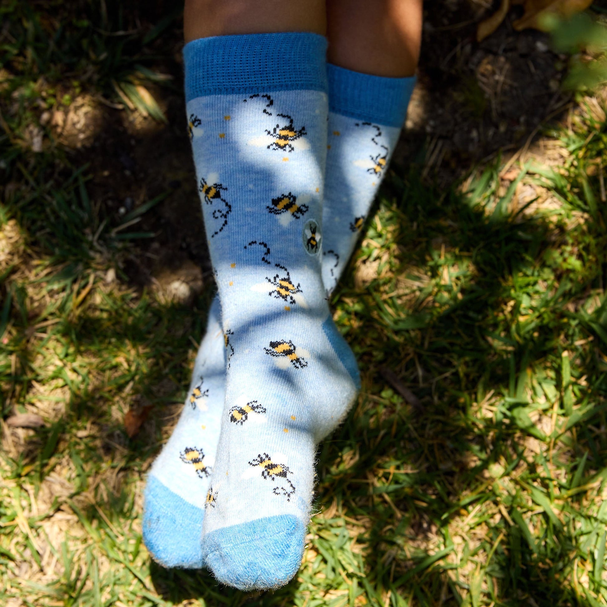 Blue socks with bee pattern worn on grass